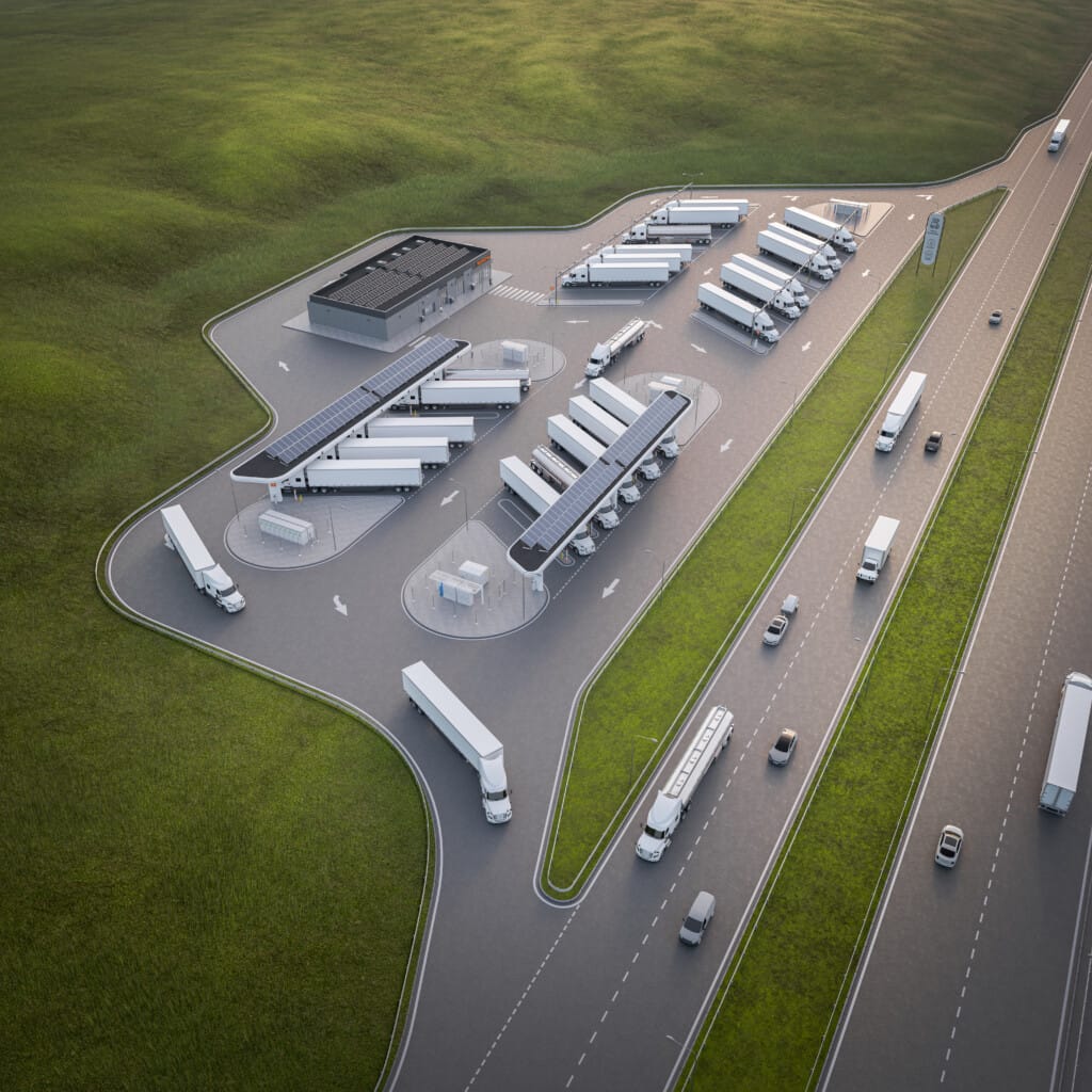 Aerial view of a modern truck rest area with parking spaces and a service building, located beside a highway in a lush green landscape.