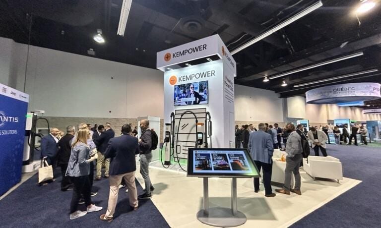 People gather around a large trade show booth with 